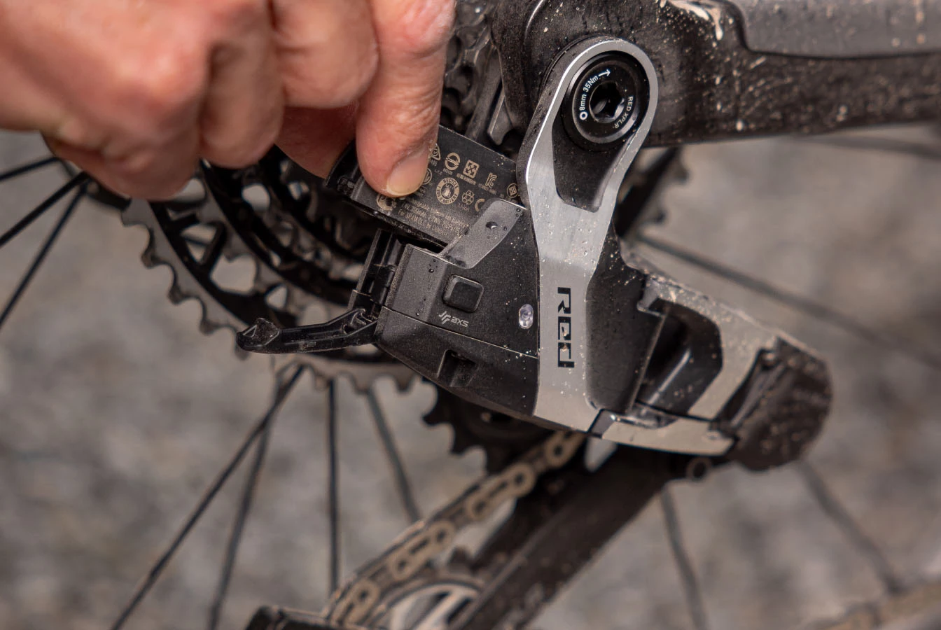 ある手が、自転車のディレイラーから電池を取り外している。.