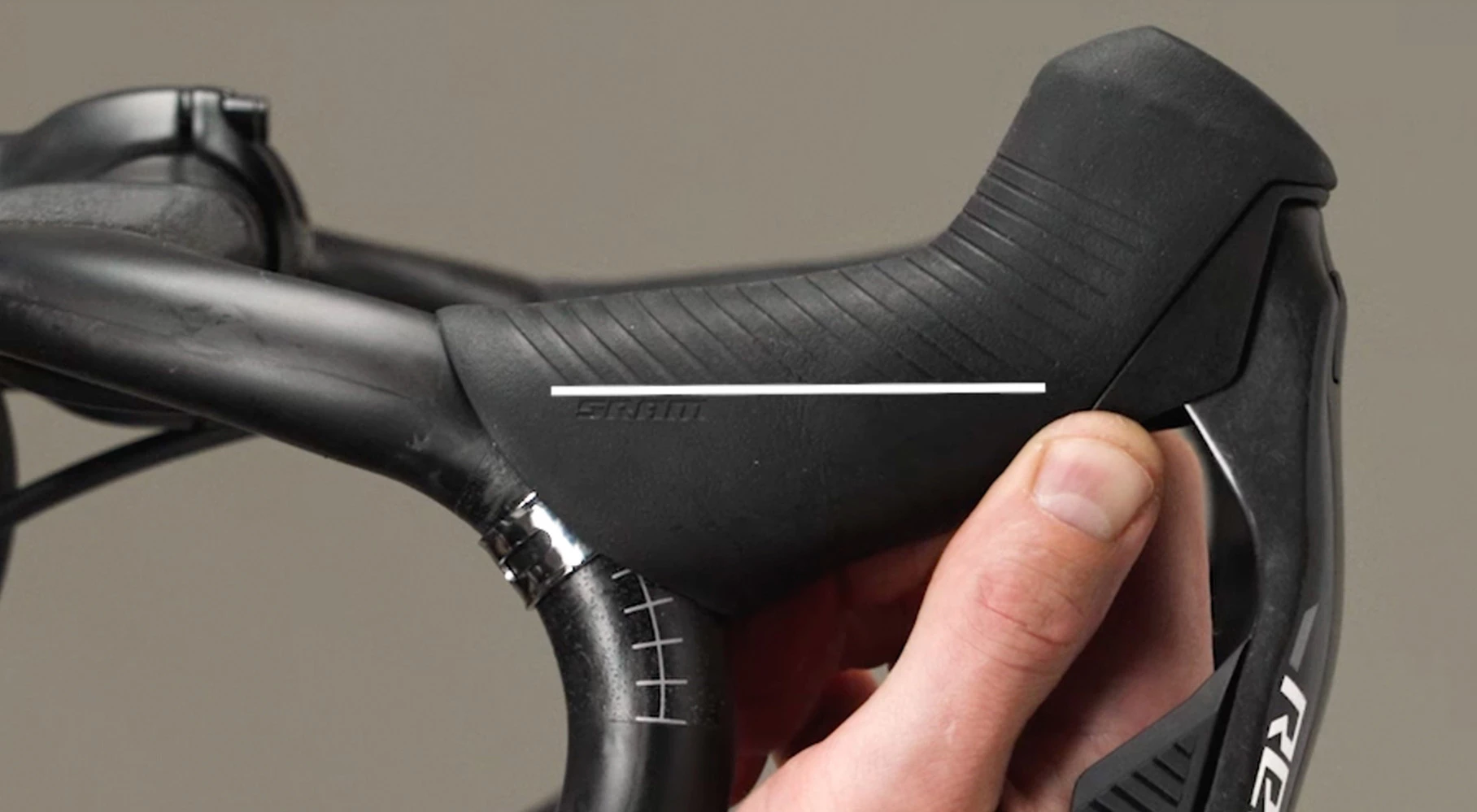 ある手が、SRAM製のロードバイク用ブレーキレバーのフードを調整している。.