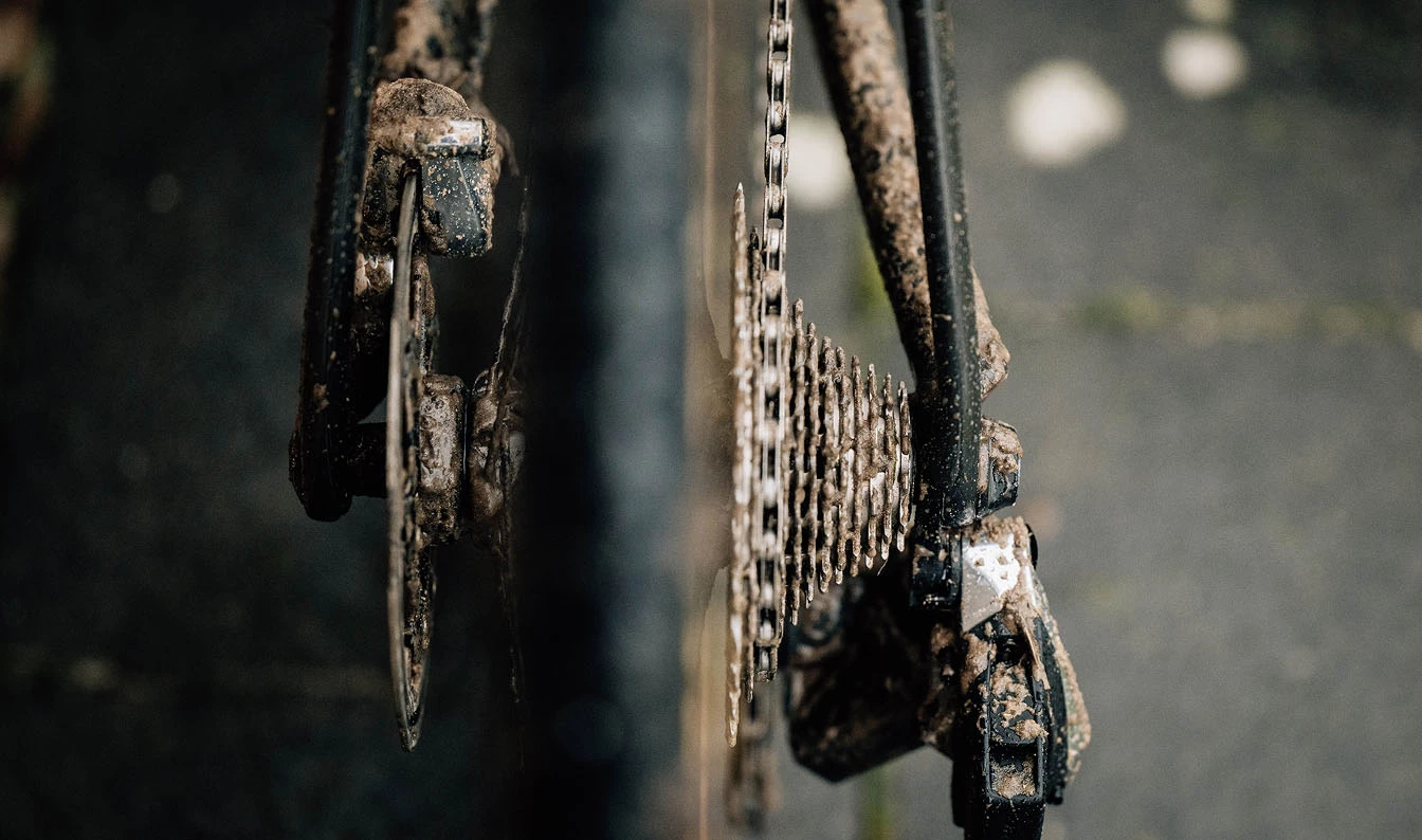 自転車のリアカセットとディスクブレーキが泥まみれになっている。.