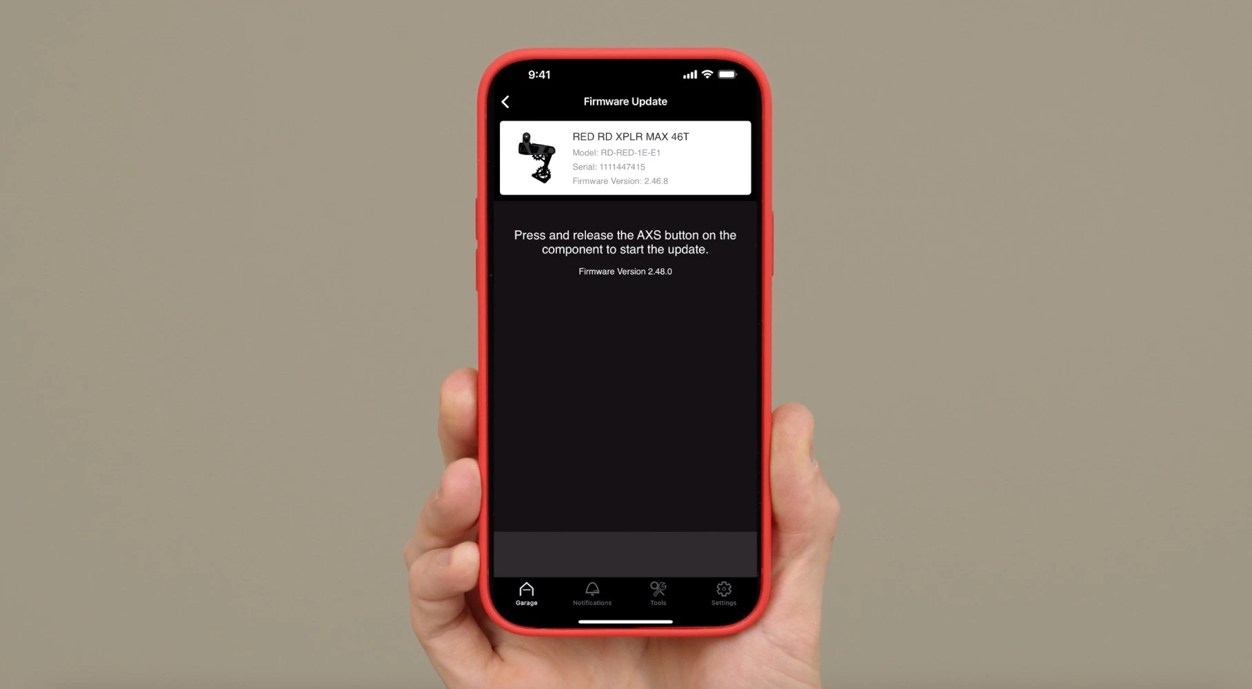 RED XPLR MAX 4T ディレイラーのファームウェア更新画面が表示されたスマートフォンを手に持つ手。.