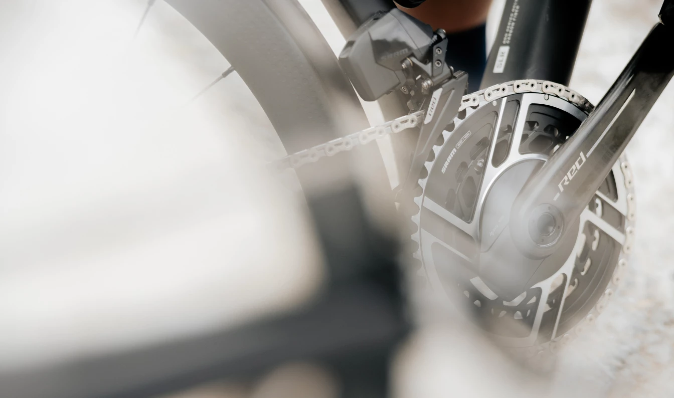 SRAM Redのクランクセットと電子式フロントディレイラーを備えた自転車のドライブトレインのクローズアップ。.