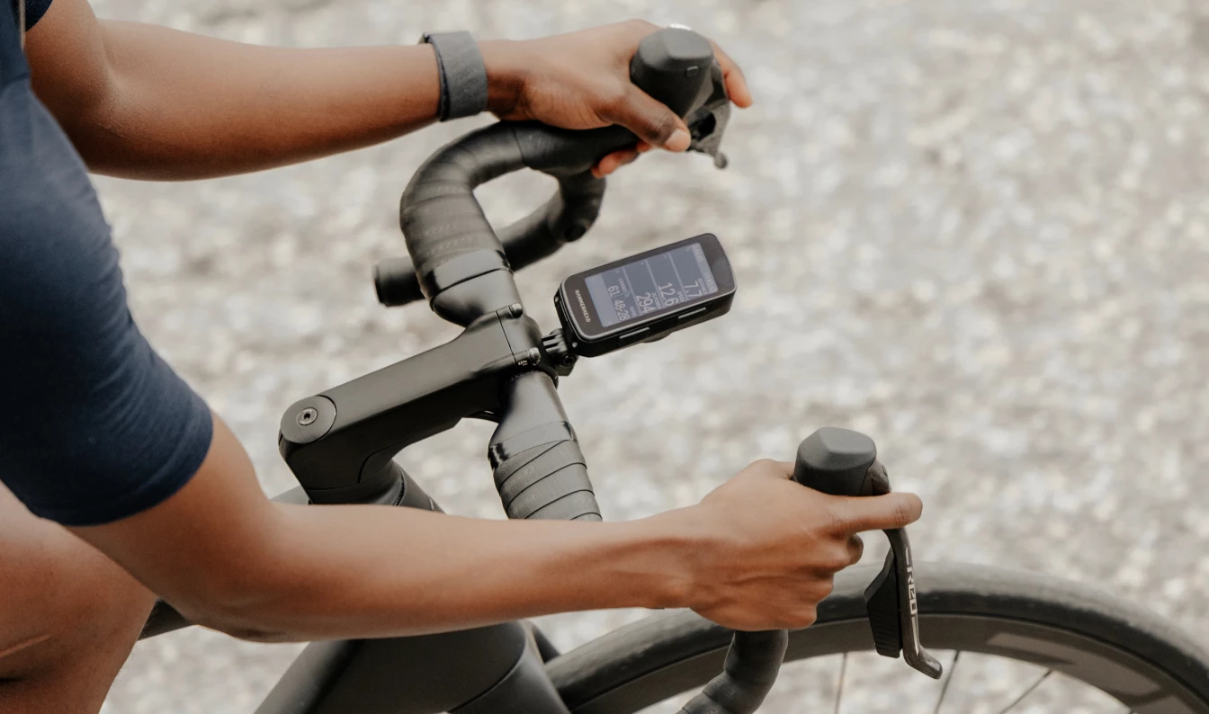 ステムにデジタルサイクルコンピュータが取り付けられたロードバイクのハンドルバーを握る人の手。.