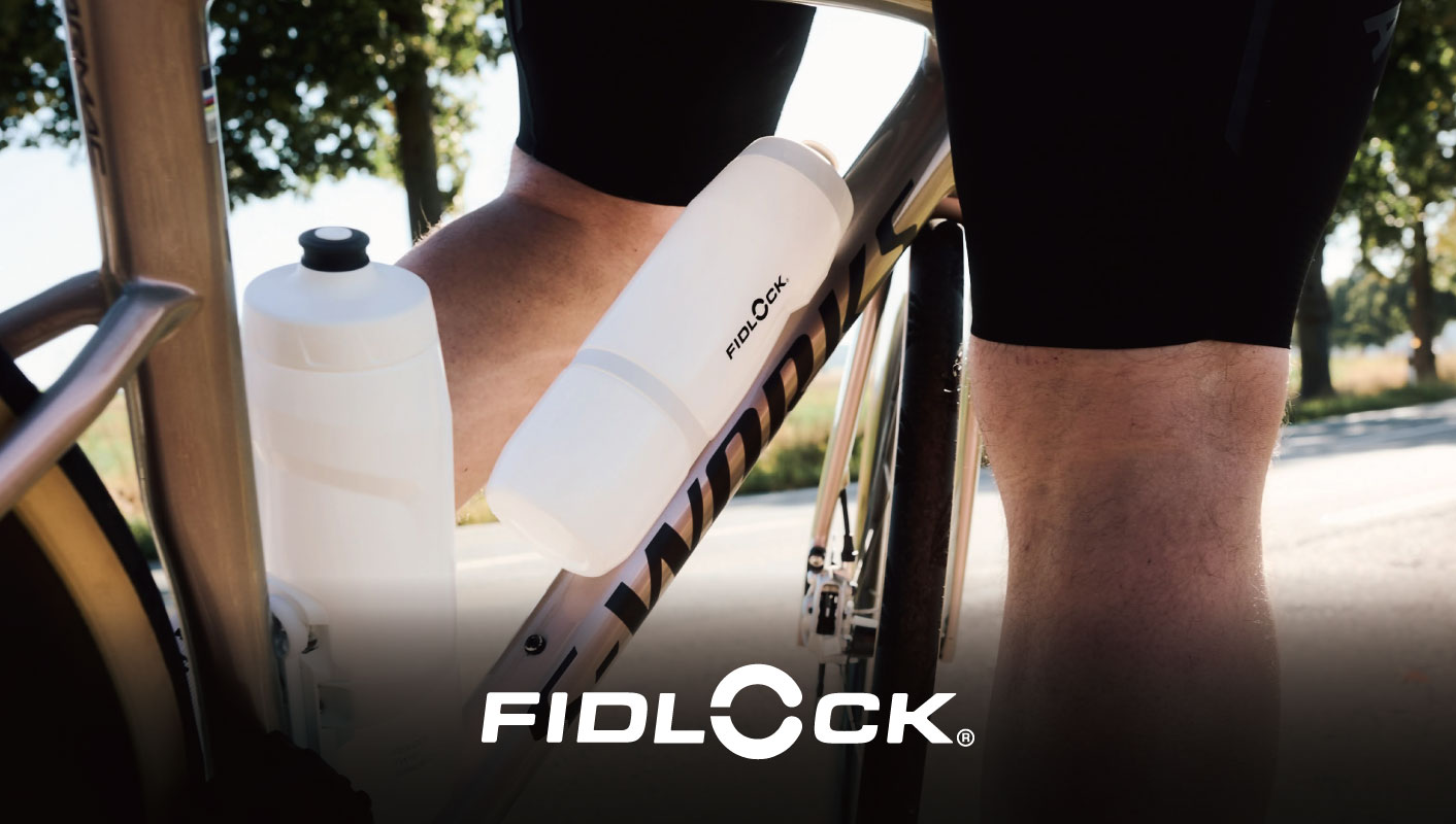 フレームに2本の白いフィドロック製の水筒を取り付けた自転車に乗っているサイクリスト。.