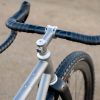 A33A0235 ROUTTのグラベルバイクのコックピットをクローズアップした写真。ハンドルバー、ステム、フロントタイヤが写っている。.