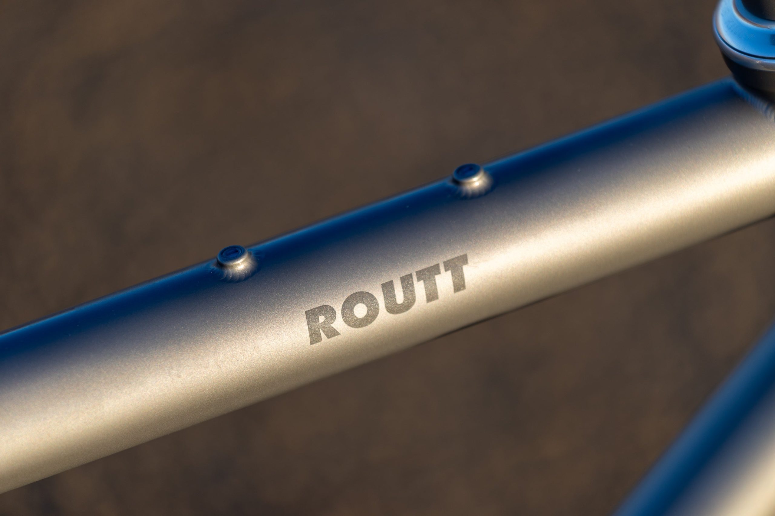 A33A0277 側面にROUTTと刻印された、灰色の自転車フレームのチューブのクローズアップ。.
