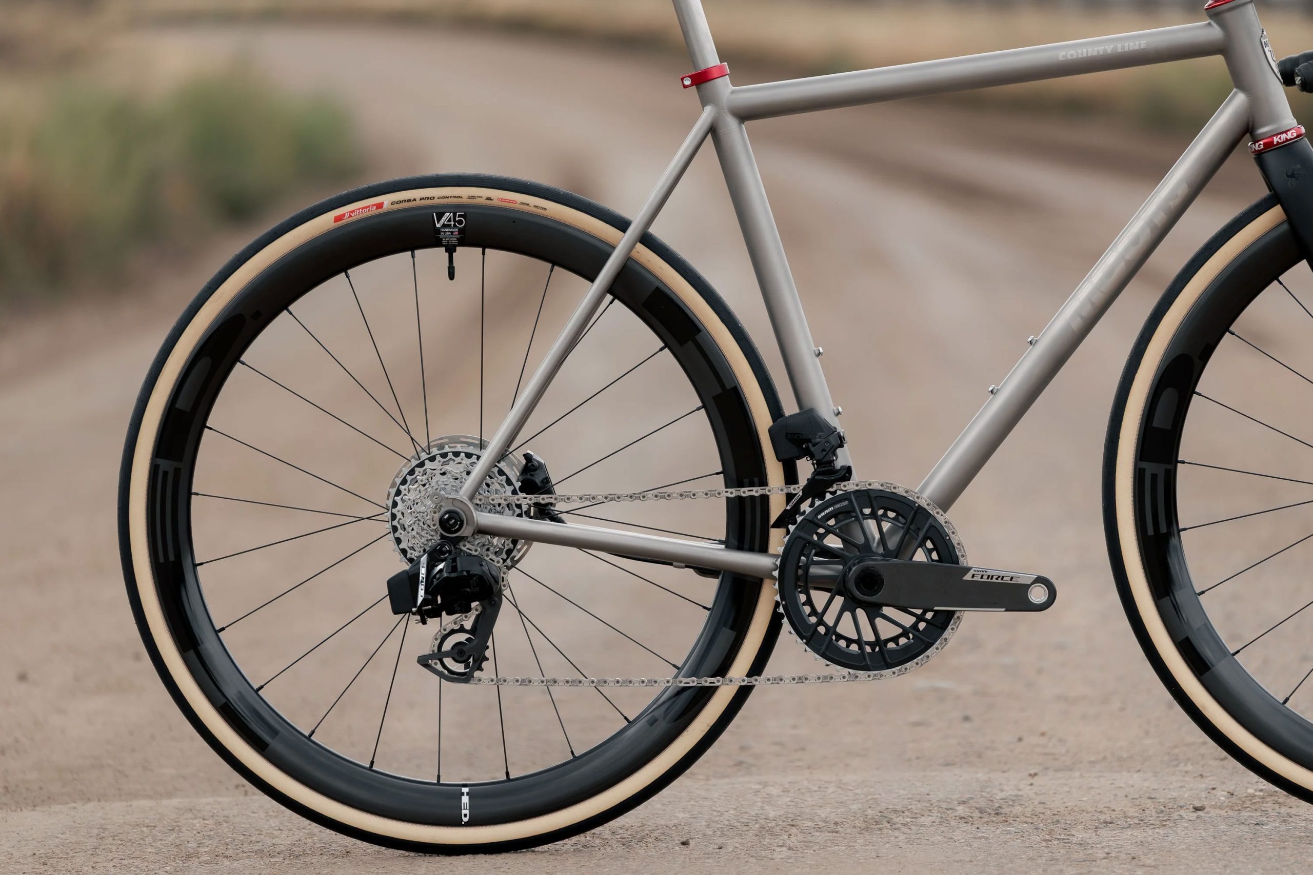 A33A1647_1e0fe523-c1d0-4b7a-a245-5780a7fe5311 ダートコースを走るCOUNTY LINE ALL-ROAD BIKEのフレームの後方からの眺め。ディープセクションのカーボンホイールと1xドライブトレインを装備している。.