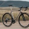 A33A1650 グレーのメタルフレーム、ドロップハンドル、ディープセクションのカーボンホイールを備えたCOUNTY LINE ALL-ROAD BIKEが、未舗装の道に停まっている。.