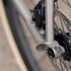 A33A1661 メタリックカラーのCOUNTY LINE ALL-ROAD BIKEフレームに搭載された、自転車のディスクブレーキとリアドロップアウトのクローズアップ写真。.