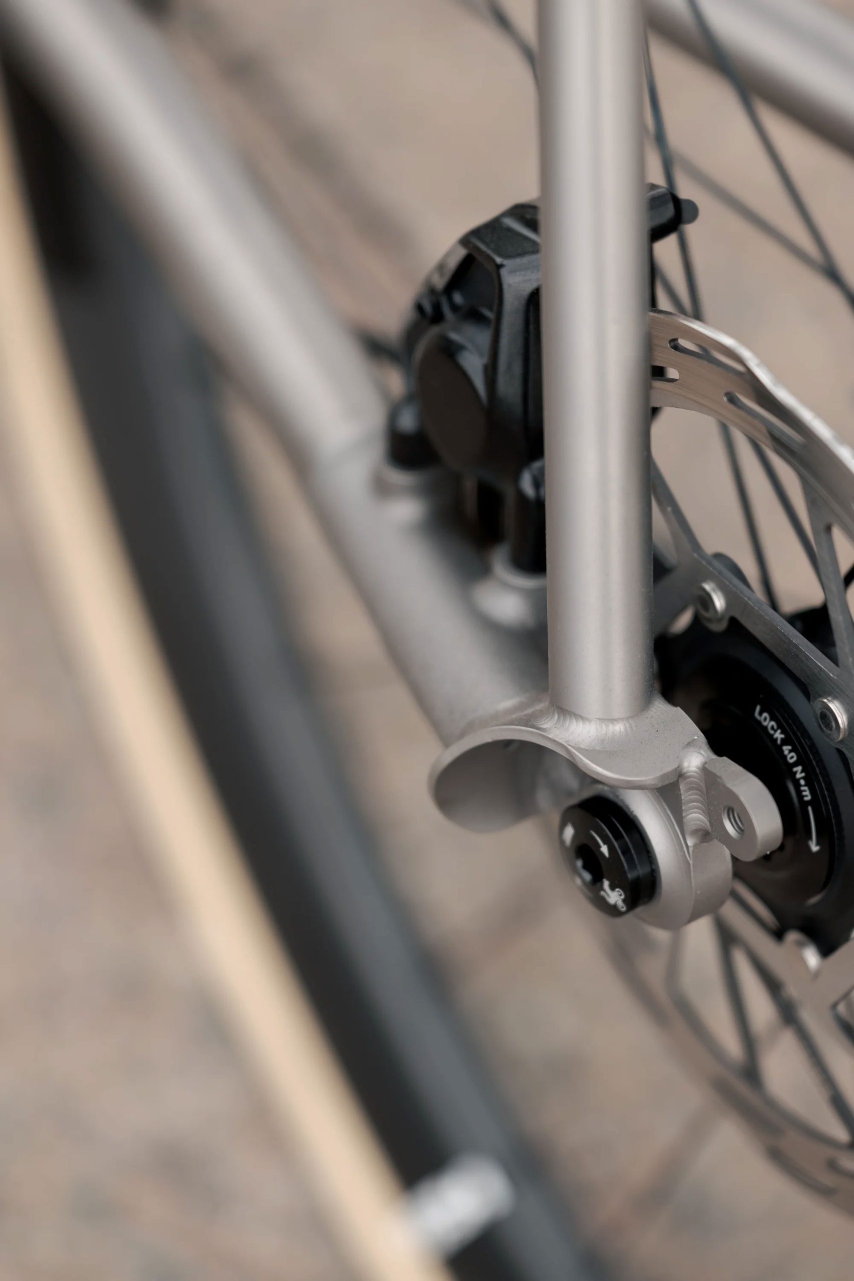 A33A1661 メタリックカラーのCOUNTY LINE ALL-ROAD BIKEフレームに搭載された、自転車のディスクブレーキとリアドロップアウトのクローズアップ写真。.