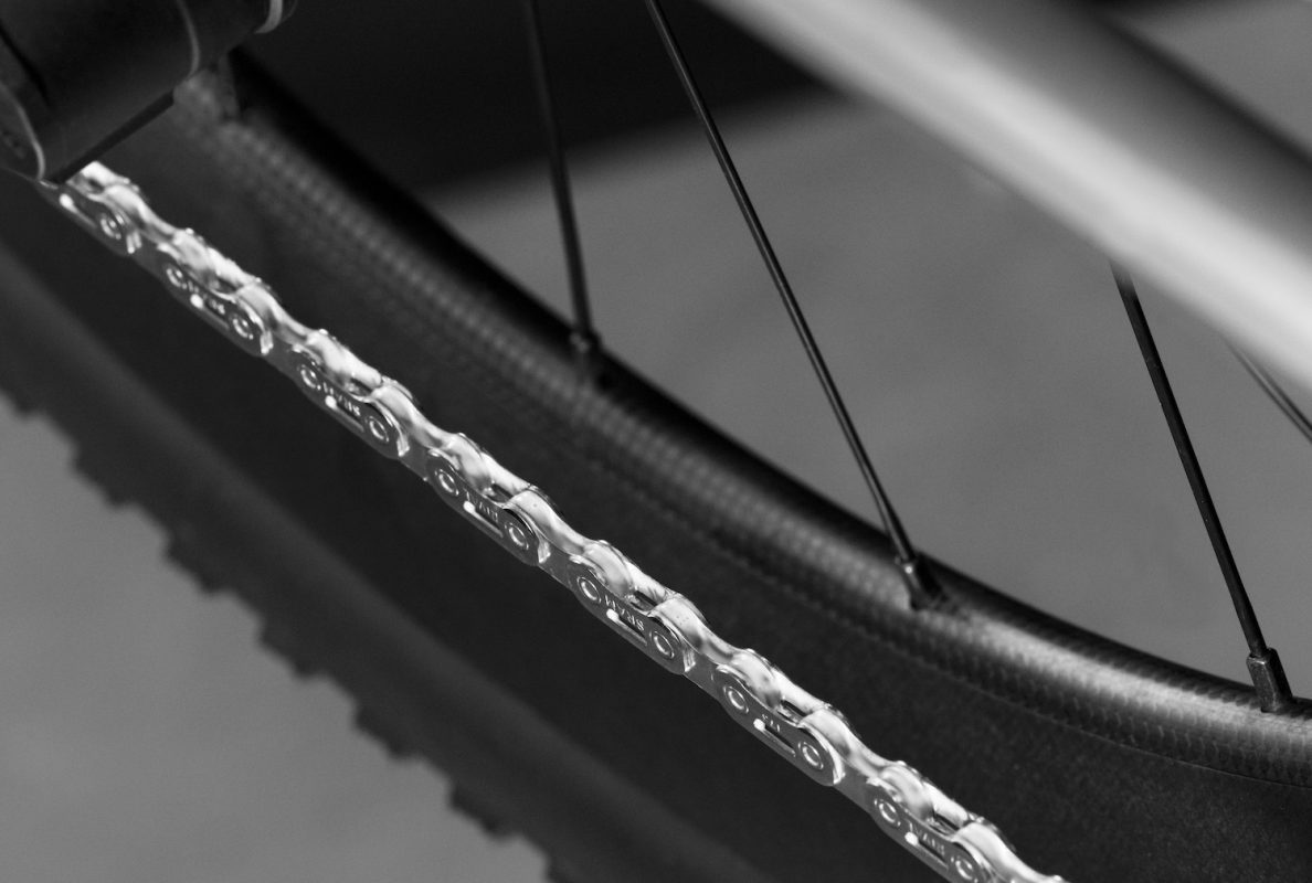 タイヤ、スポーク、金属チェーンを白黒で示した自転車の車輪のクローズアップ。.