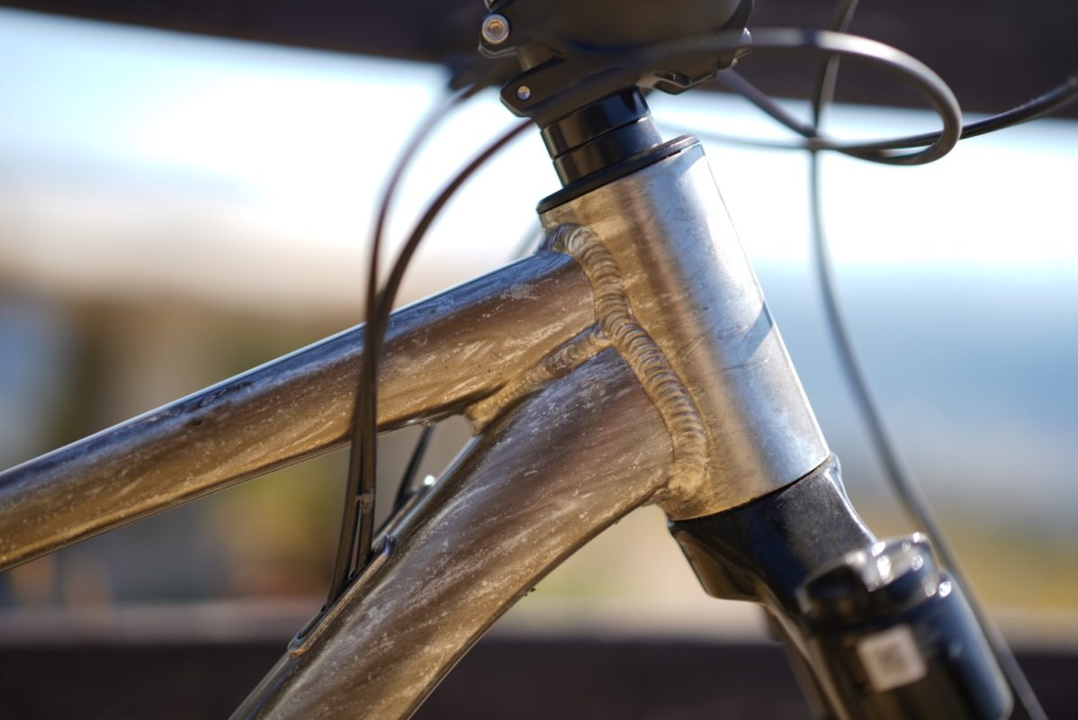 ヘッドチューブ、トップチューブ、および溶接された金属の接合部が見える自転車フレームのクローズアップ。.