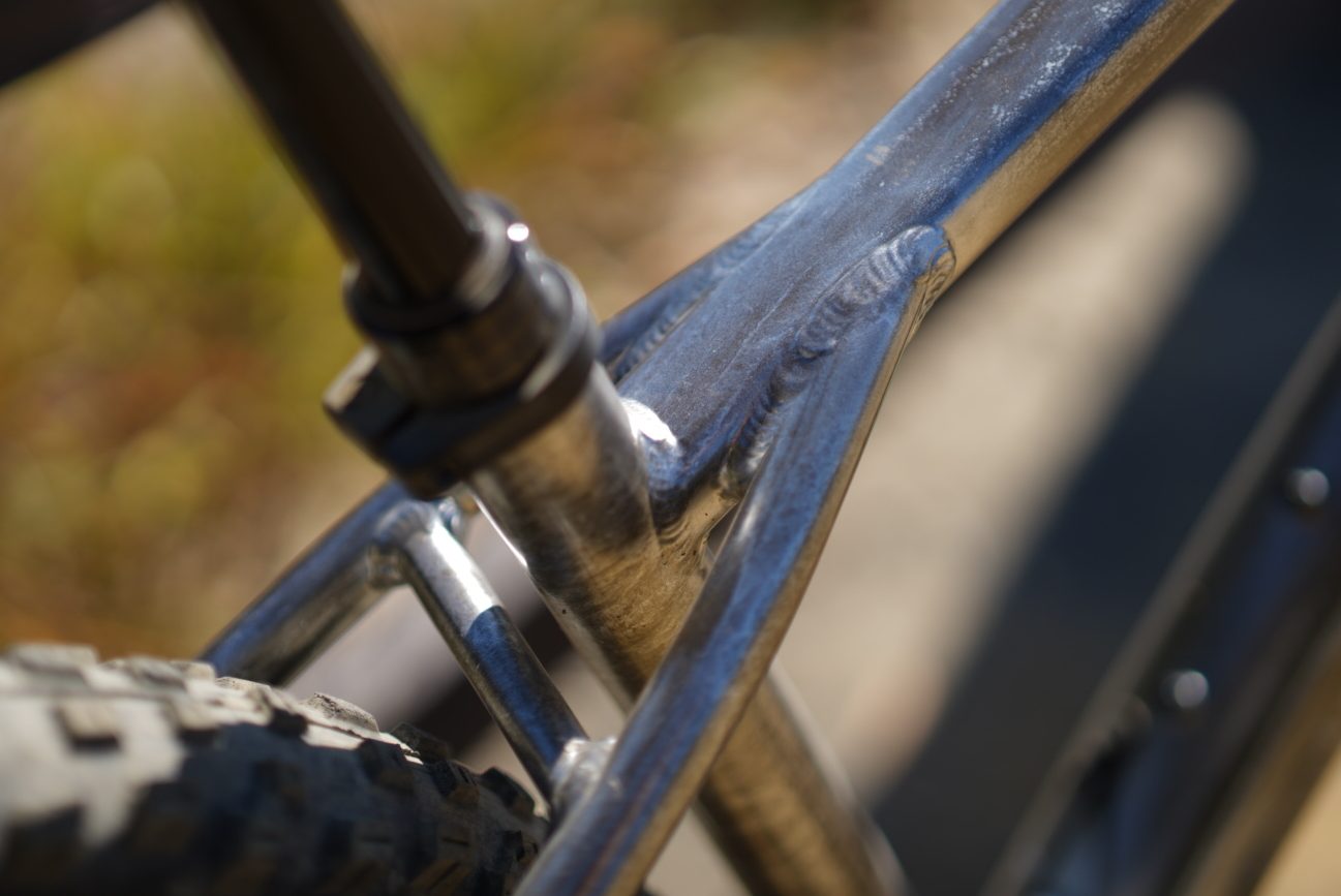 自転車のフレームのクローズアップ写真。シートチューブとの接合部に金属の溶接跡が見え、ドロッパーシートポストが取り付けられている。.
