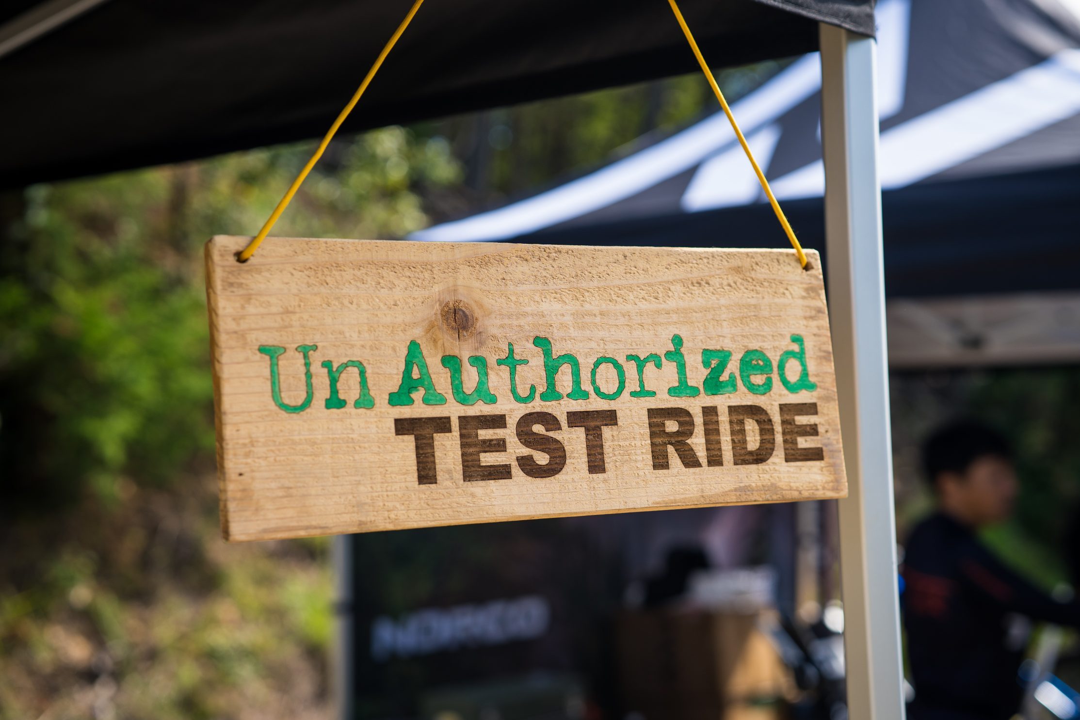 テントの骨組みから吊り下げられた木製の看板には、無許可の試乗と書かれている。.