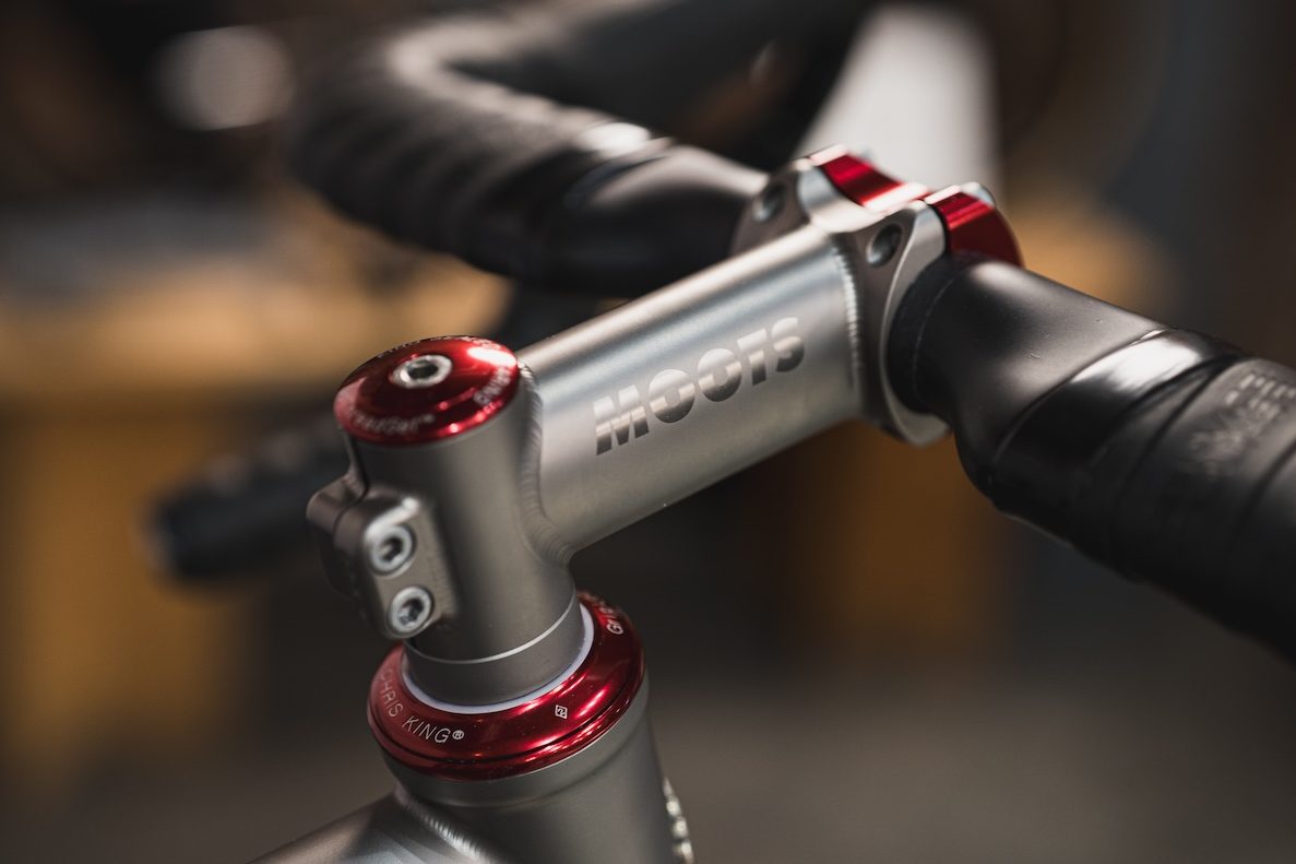 MOOTSのロゴが入った自転車のハンドルステムのクローズアップ。赤いメタリック調のボルトとクリス・キング製のヘッドセットが取り付けられている。.