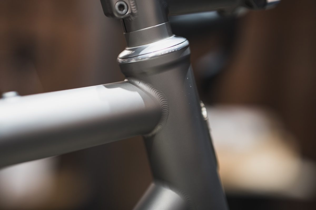 自転車の金属製フレームのヘッドチューブとトップチューブの溶接部のクローズアップ。.