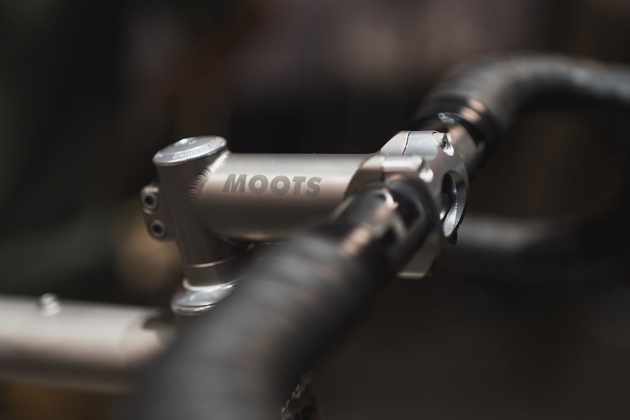 シルバーのMoots製自転車ステムと、黒いバーテープが巻かれたハンドルバーのクローズアップ写真。.