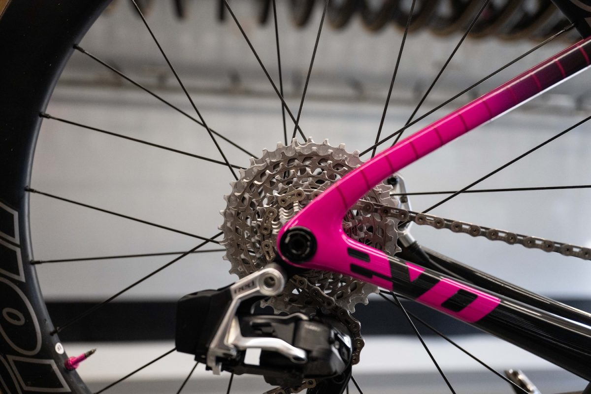 ギアカセット、ディレイラー、ピンクと黒のフレームの一部が見える自転車のリアホイールのクローズアップ。.