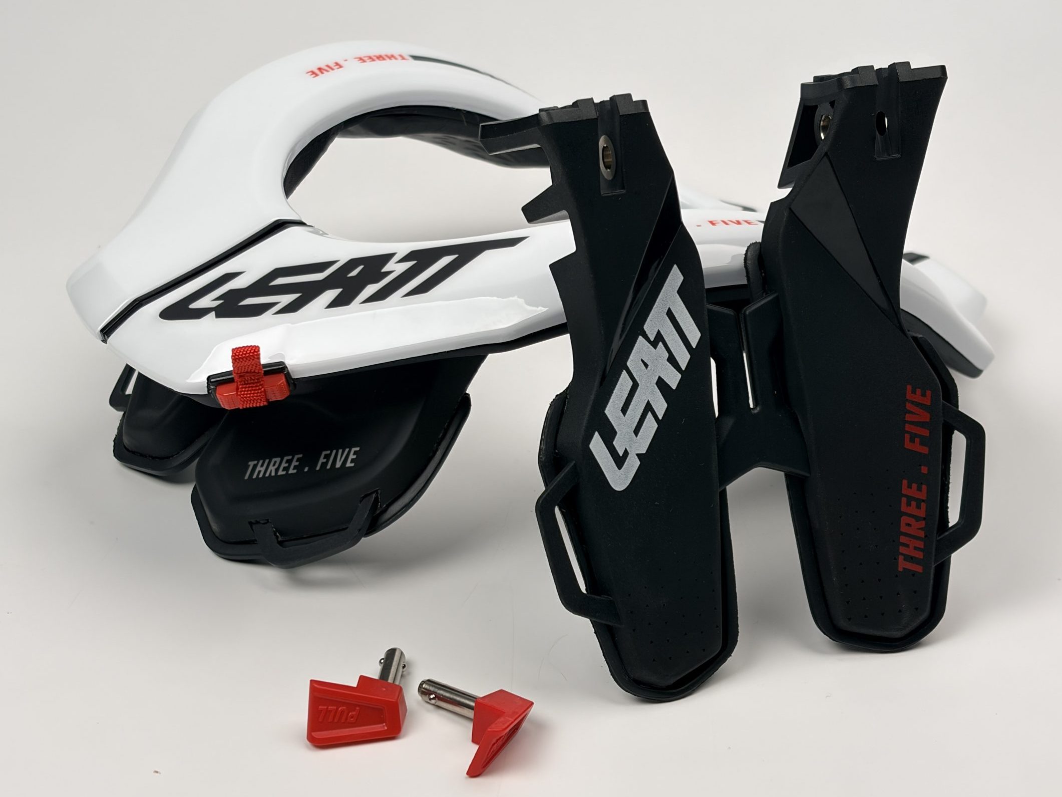 Leatt 3.5 ネックブレース。胸部と背部のストラットが分離しており、赤いリリースピンが2つ付いています。.