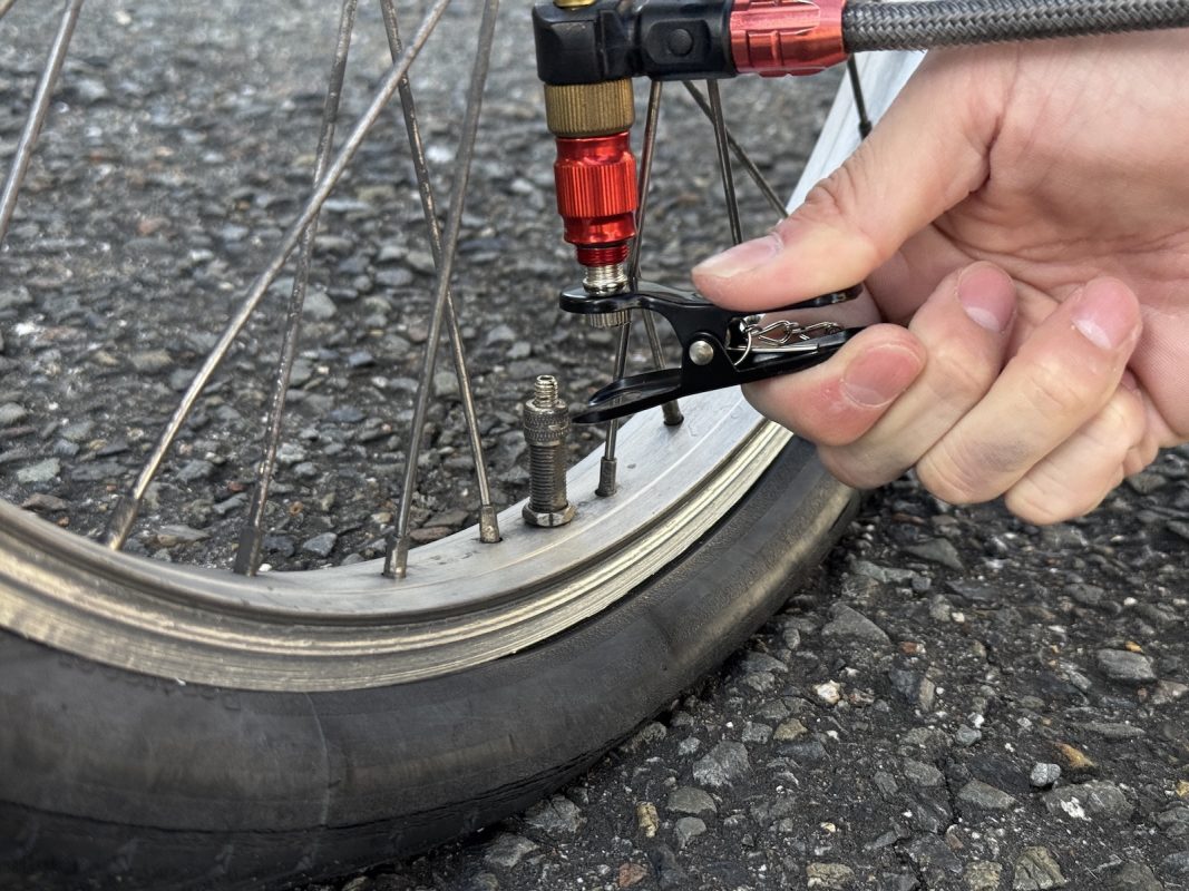 自転車のタイヤにノズルを取り付け、タイヤに空気を入れる手。.