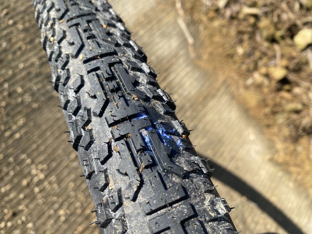 パンクして青いシーラントが漏れている自転車のタイヤのトレッドのクローズアップ写真。.