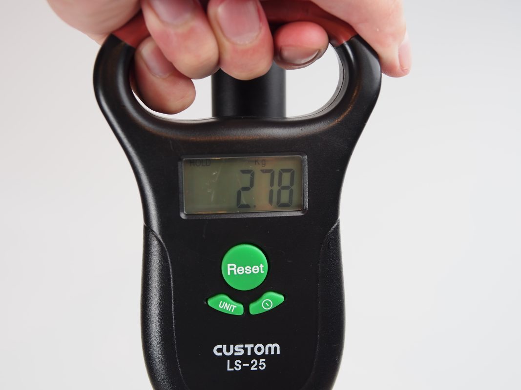 2.78 kgと表示されたデジタル荷物用はかりを手に持つ手。.