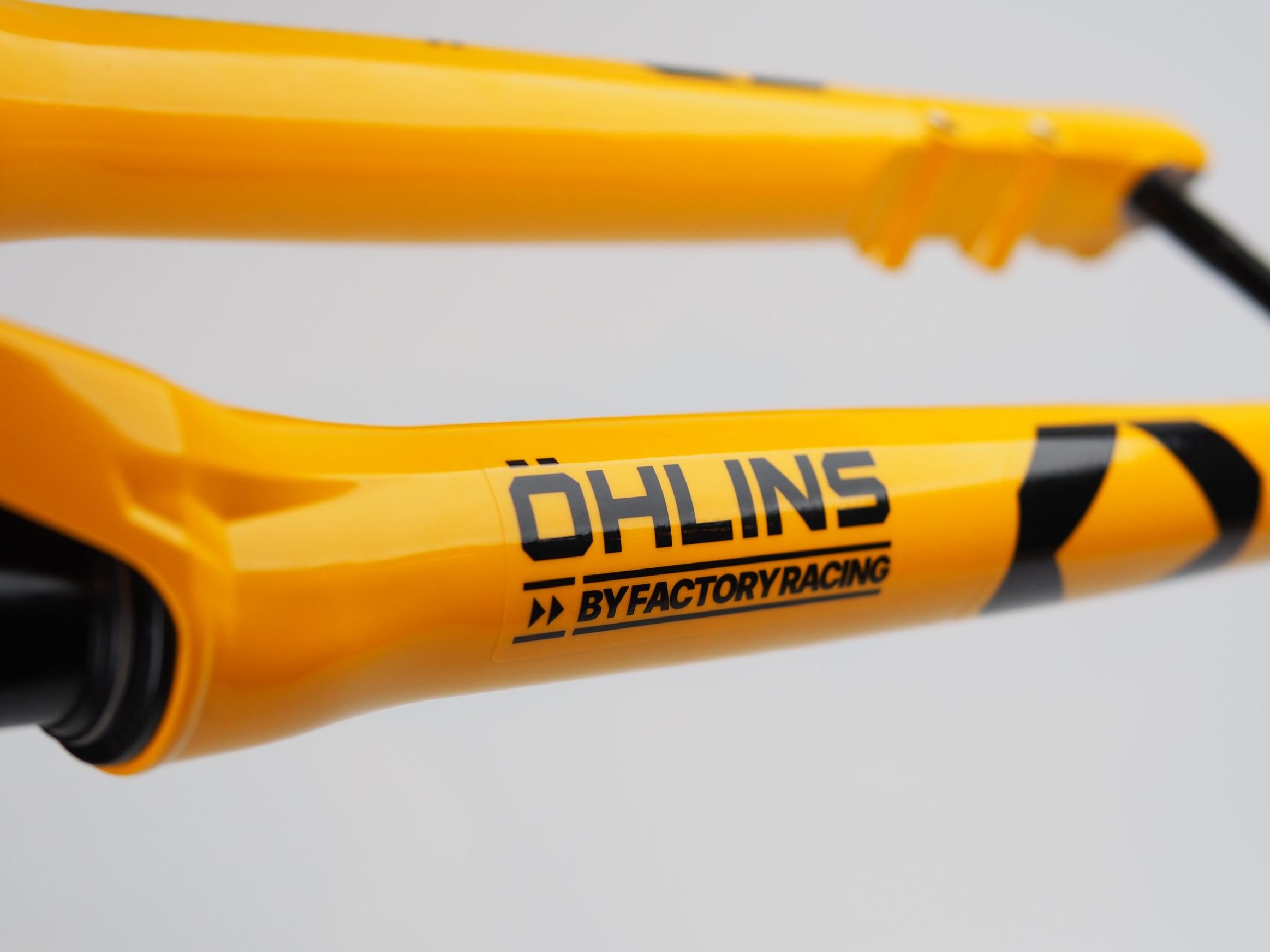 Öhlins Factory Racingのロゴが入った、鮮やかな黄色の自転車用サスペンションフォーク。.