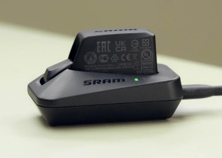 クレードルで充電中のSRAMバッテリー。電源が入っていることを示す緑色のLEDが点灯しています。.
