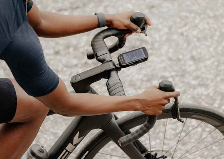 トレック製の自転車のドロップハンドルに手を置いたサイクリスト。ステムにはデジタルサイクルコンピュータが取り付けられている。.