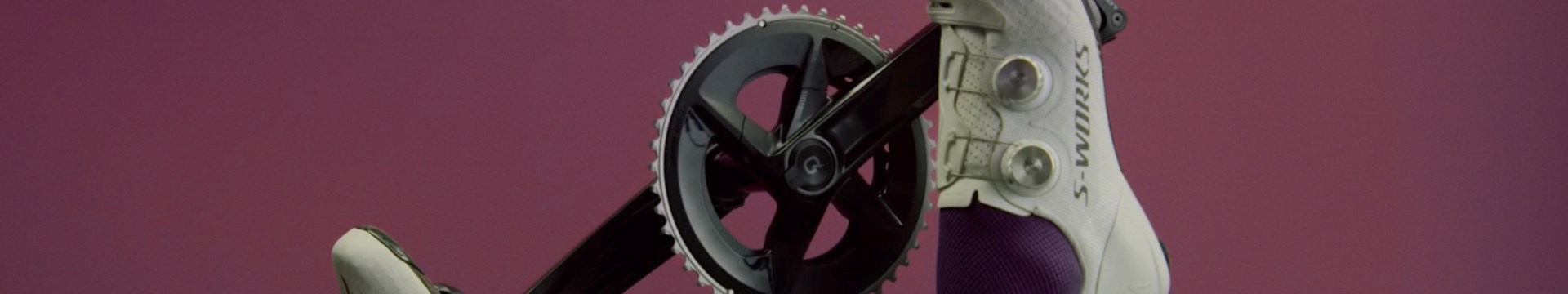自転車のクランクセットと、ダイヤル式締め付けシステムを備えた白いS-Worksサイクリングシューズのクローズアップ。.