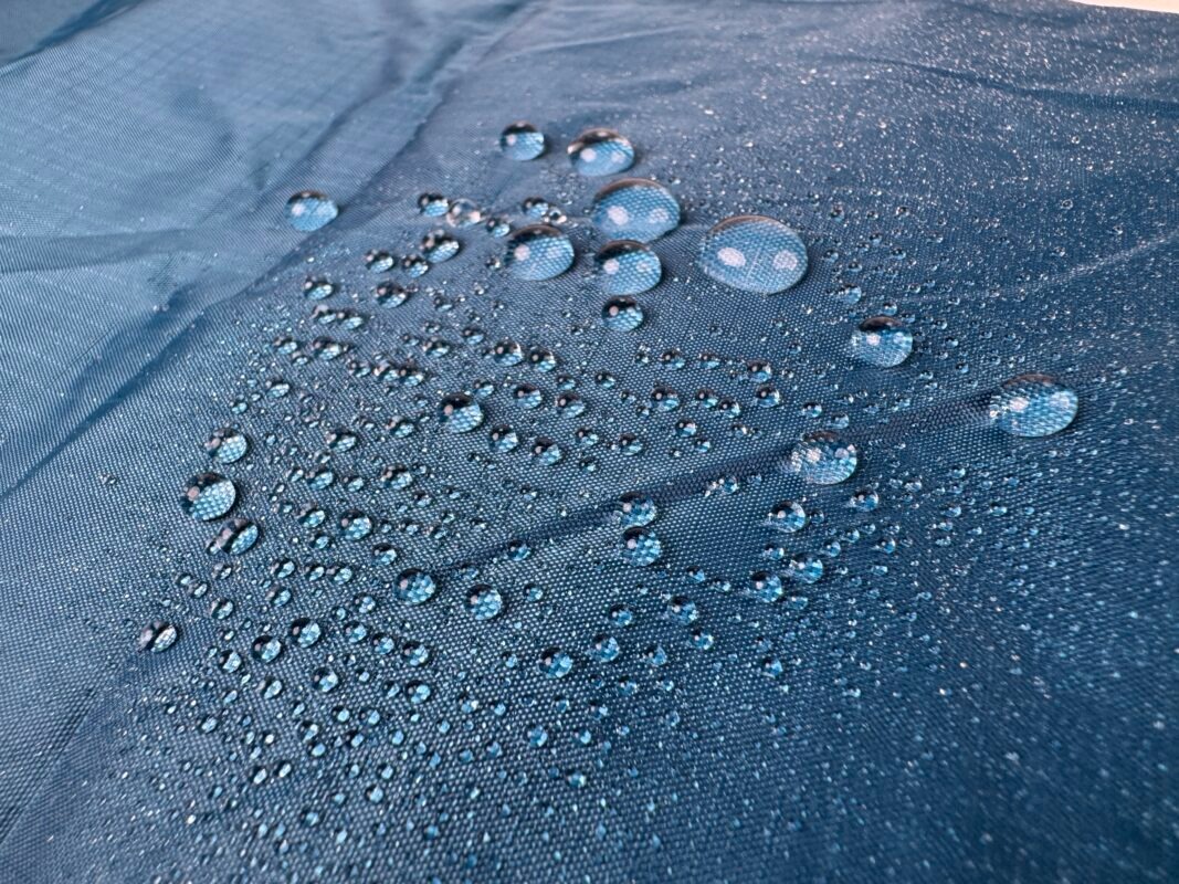 青い撥水加工の生地の表面に、水玉が並んでいる。.