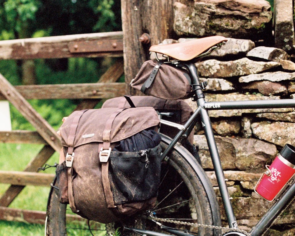 imgi_36_f8115ae508c0431e76d3b262dbb935df38870058_Travelling_Bags_Haul_Half_Haul_All_wander_no_wobble 自転車の後部に装着された、サイドにメッシュポケット付きのHALF HAUL PANNIER SEAL BROWNバッグ。.
