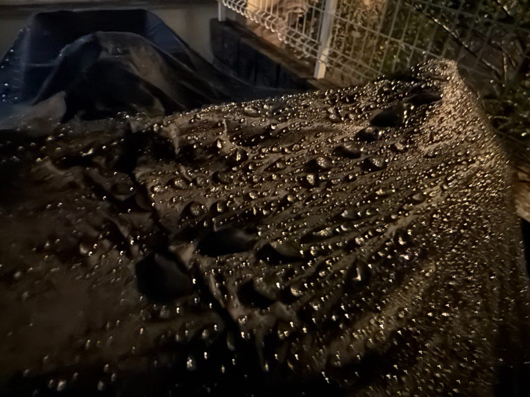 夜、暗く、質感のある表面に降り注ぐ雨粒。.