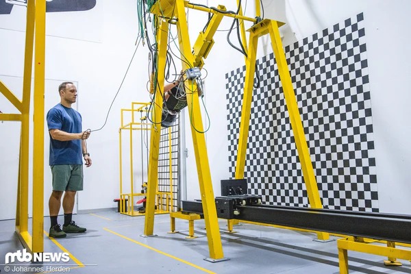 黄色い測定裝置とチェックの自变板が置かれた研究室で人物が作業している写真