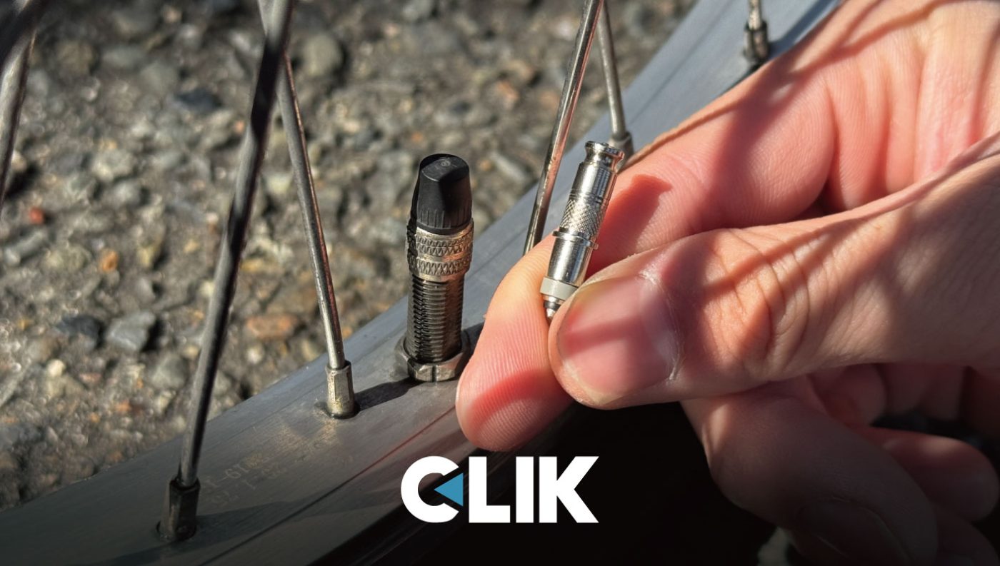 自転車のホイールリムのバルブステムの横で、自転車のプレスタバルブのコアを持つ手。.