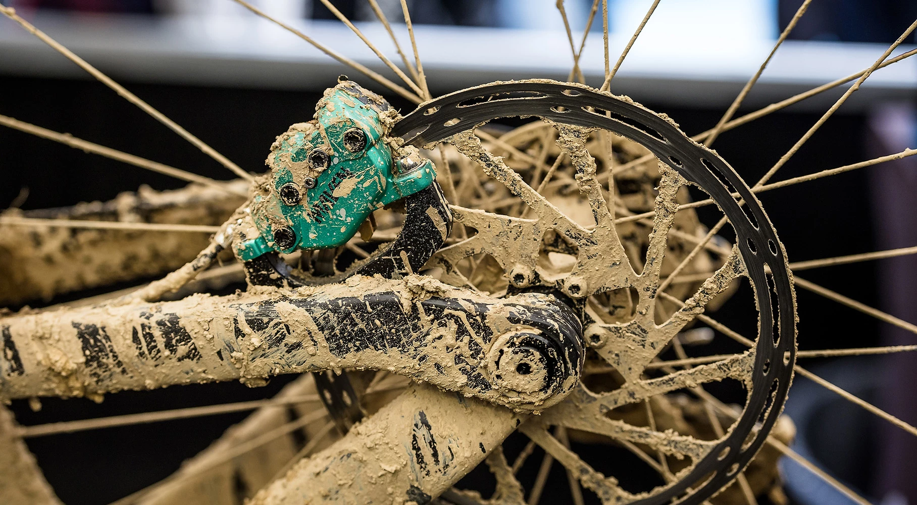 マウンテンバイクのディスクブレーキと、分厚い泥にまみれたホイールのスポーク。.
