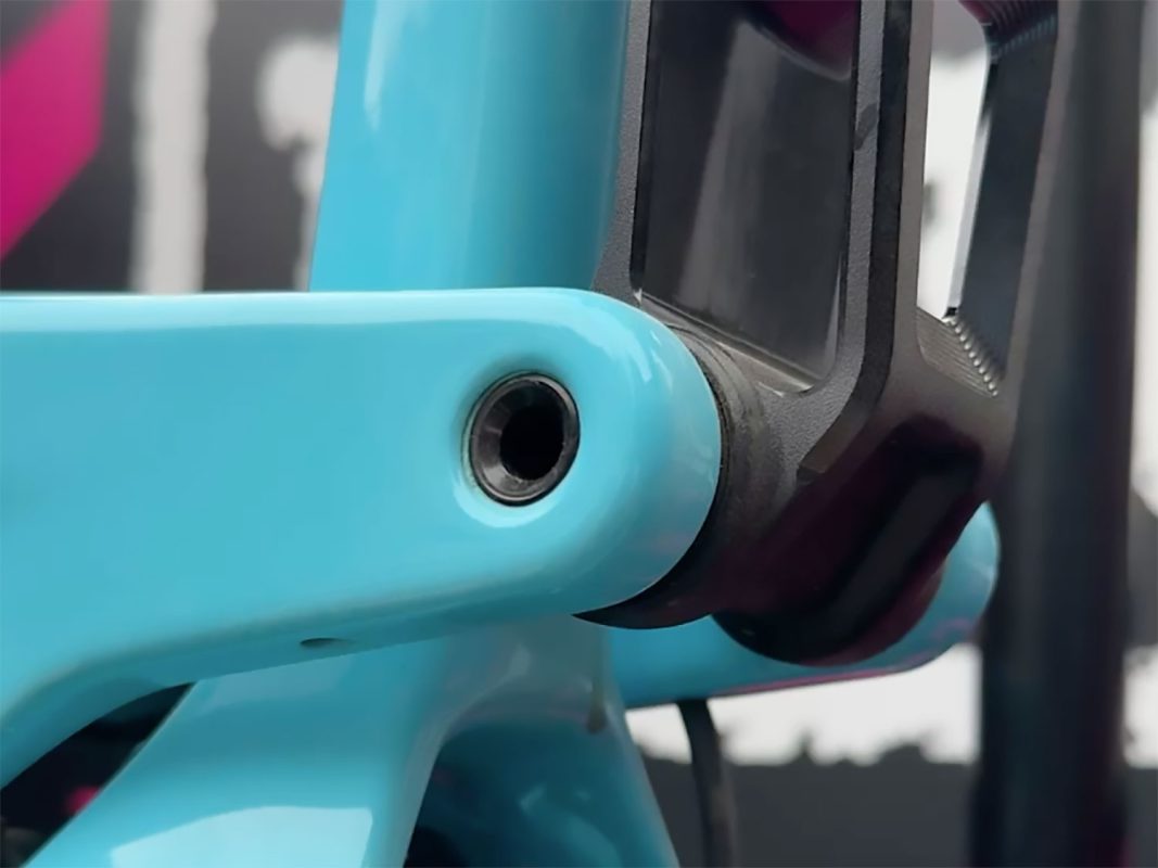 青い自転車のフレームのピボットポイントとボルトのクローズアップ。.