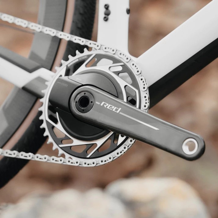 白い自転車のフレームに取り付けられた、SRAM Redのクランクセットとチェーンリングのクローズアップ写真。.