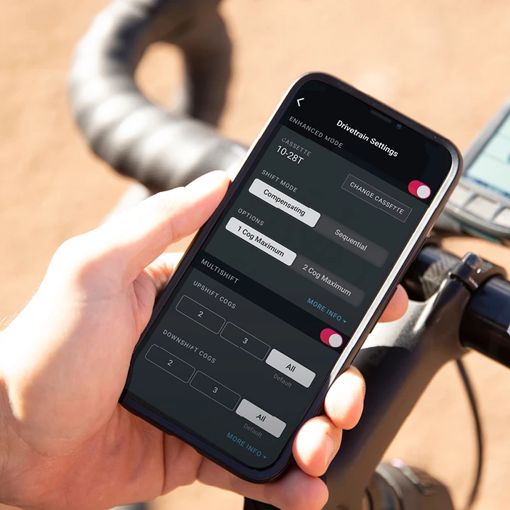 ある手が、自転車のドライブトレイン設定アプリが表示されたスマートフォンを握っている。.