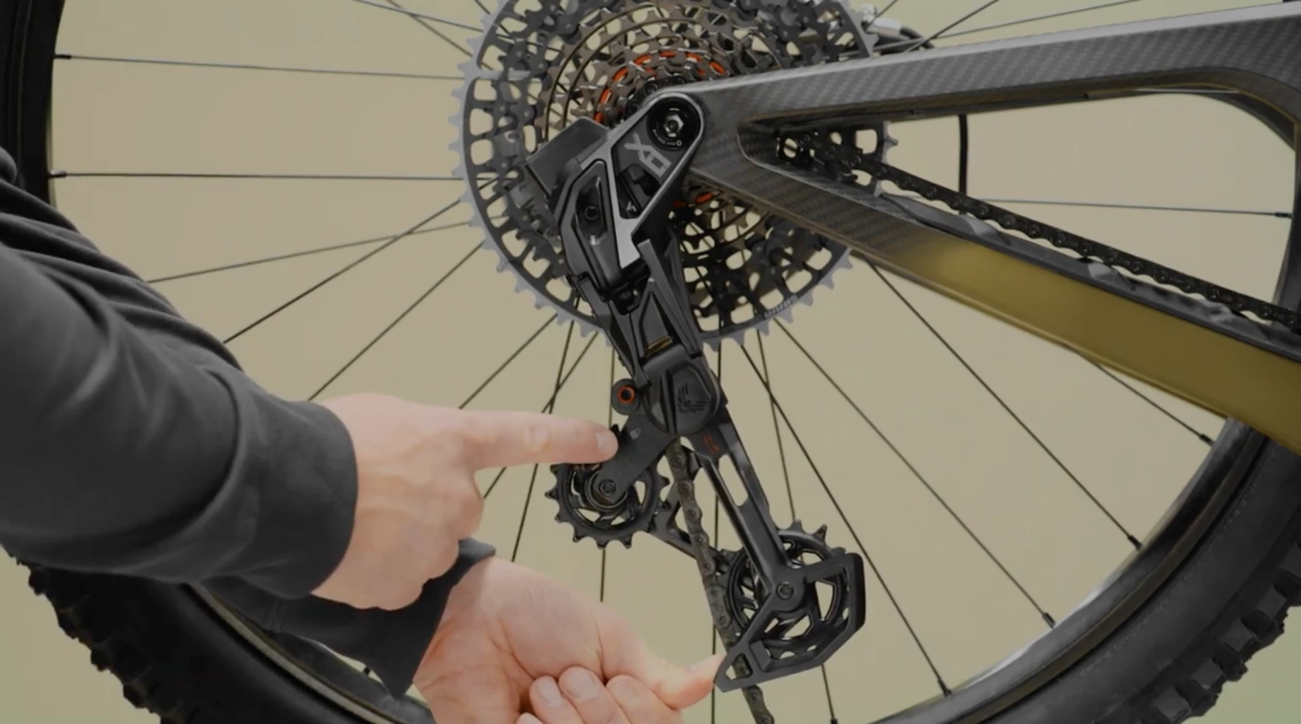 ある人物の手が、マウンテンバイクのリアディレイラーの各部品を指し示している。.