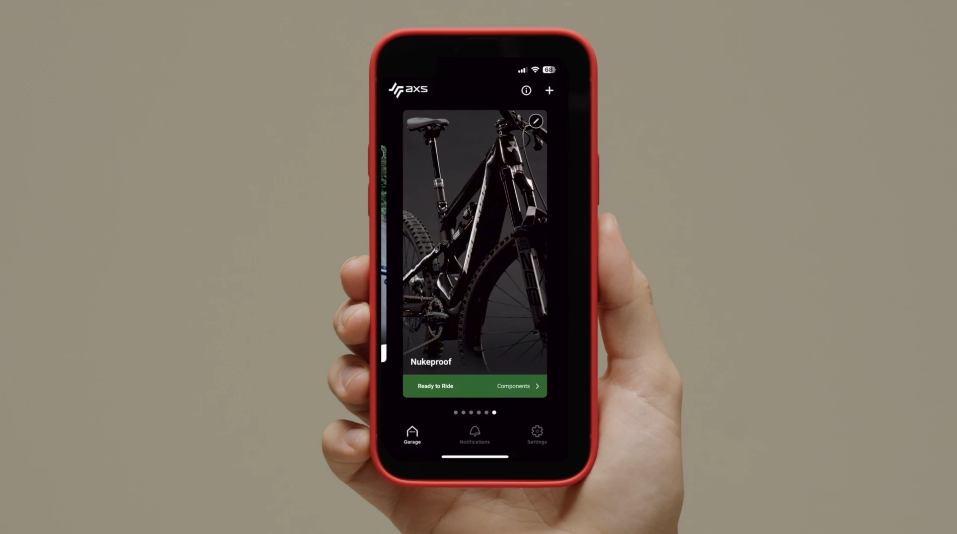 SRAM AXSアプリが表示されたスマートフォンを手に持ち、画面にはNukeproofのマウンテンバイクが表示されている。.