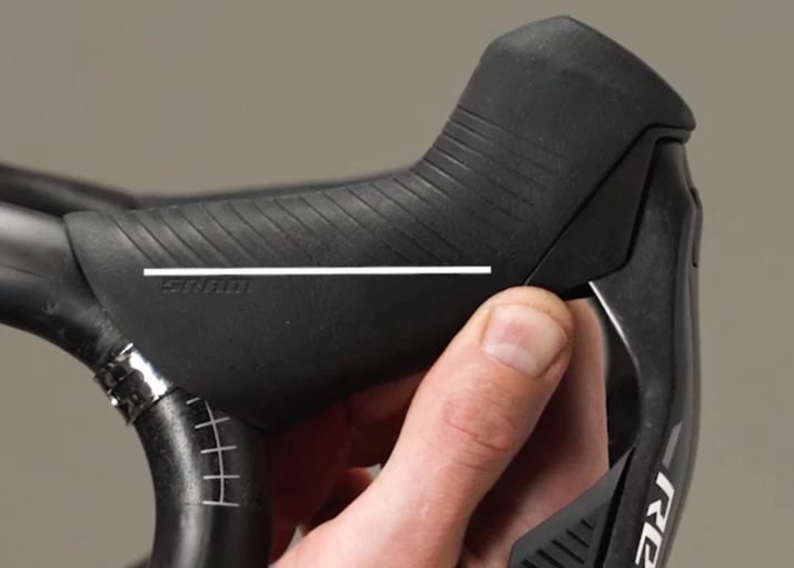 黒いSRAM製の自転車用ブレーキレバーとフードを握った手。.