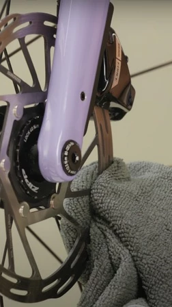マイクロファイバーの布で自転車のディスクブレーキを拭いている手。.