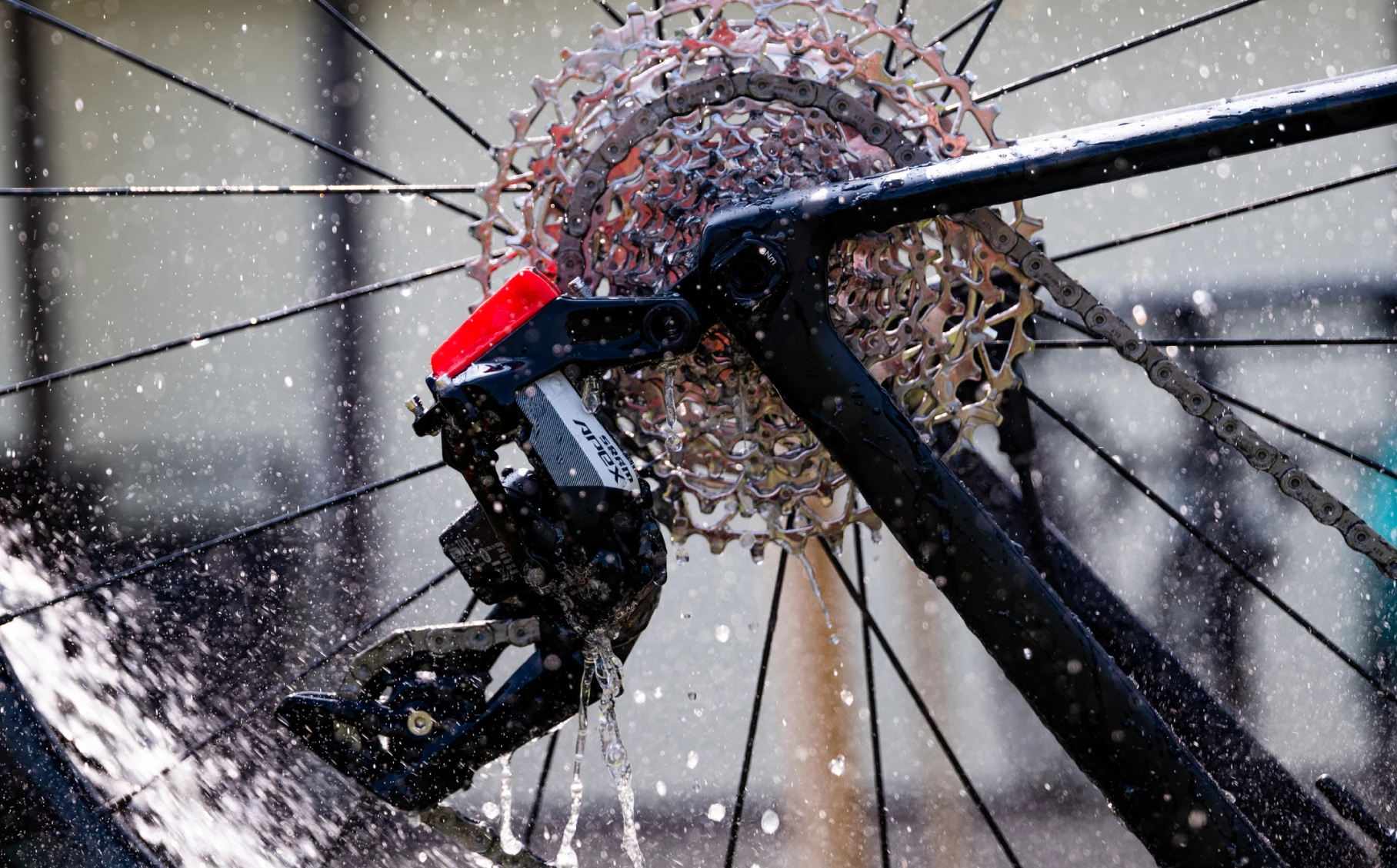 自転車リアディレイラーとカセットに水が吹きかけられている様子のクローズアップ。.