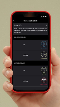 SRAM AXSのConfigure Controls画面が表示されたスマートフォンを手に持ち、左右のコントローラーボタンにアクションを割り当てるオプションが表示されている様子。.