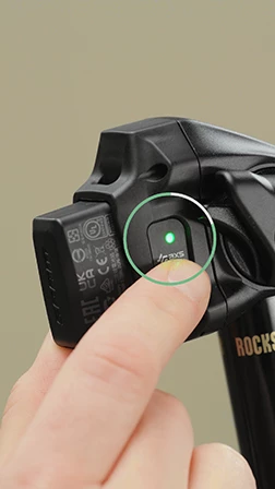 指が、緑色の光が点灯している黒い電動自転車の部品のボタンを押す。.