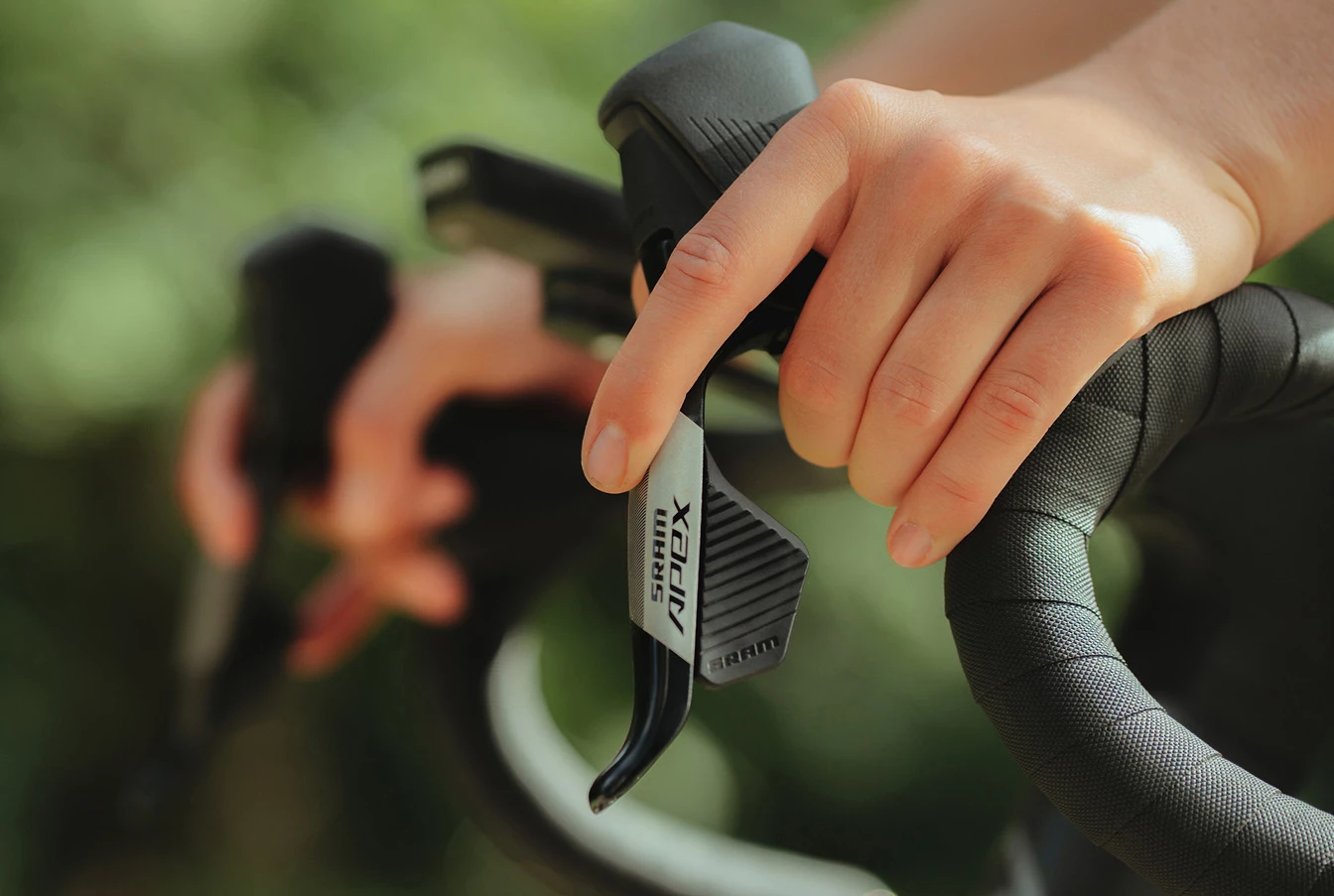 SRAM Apexのブレーキレバーが付いた自転車のハンドルを握る手。.