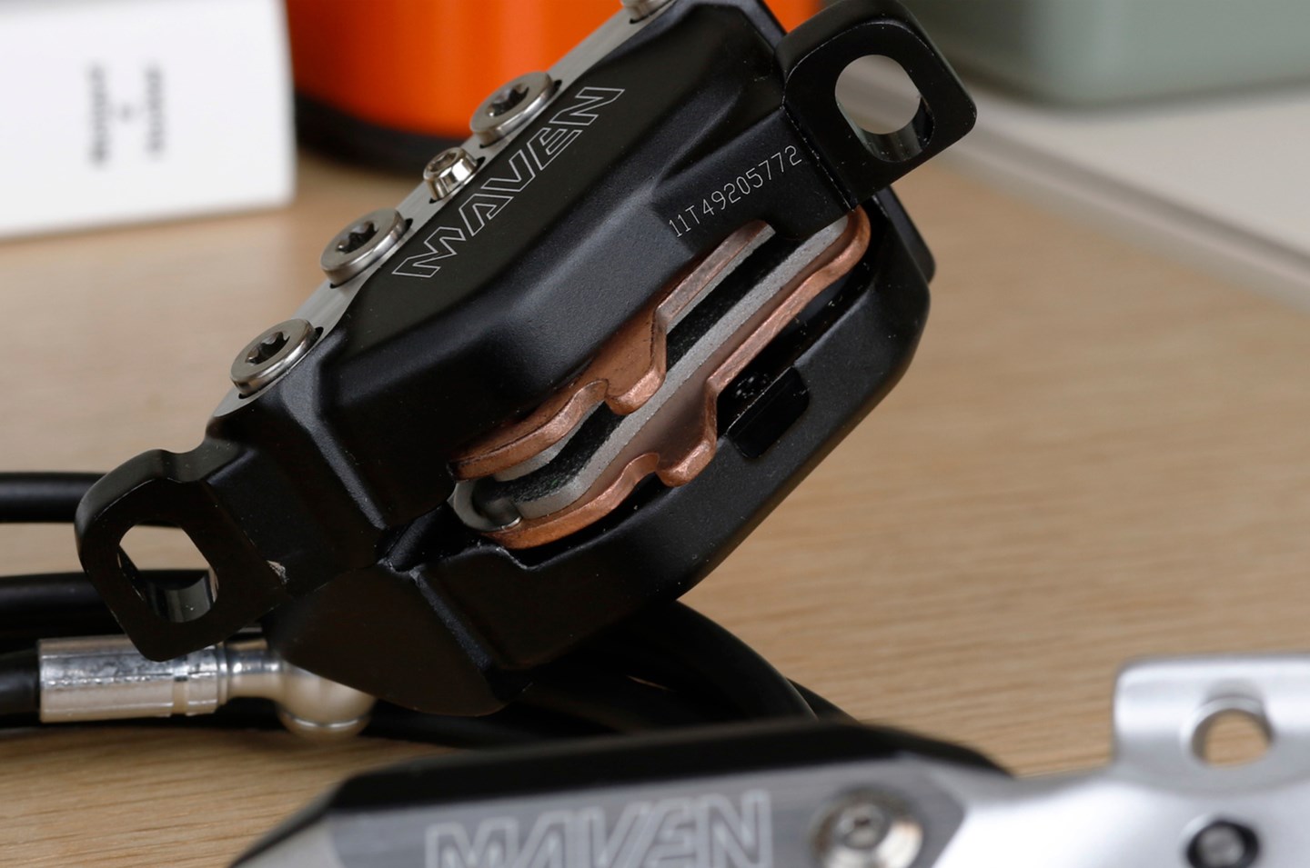 ブラックのSRAM Maven油圧式ディスクブレーキキャリパー。銅色のブレーキパッドが見える仕様。.