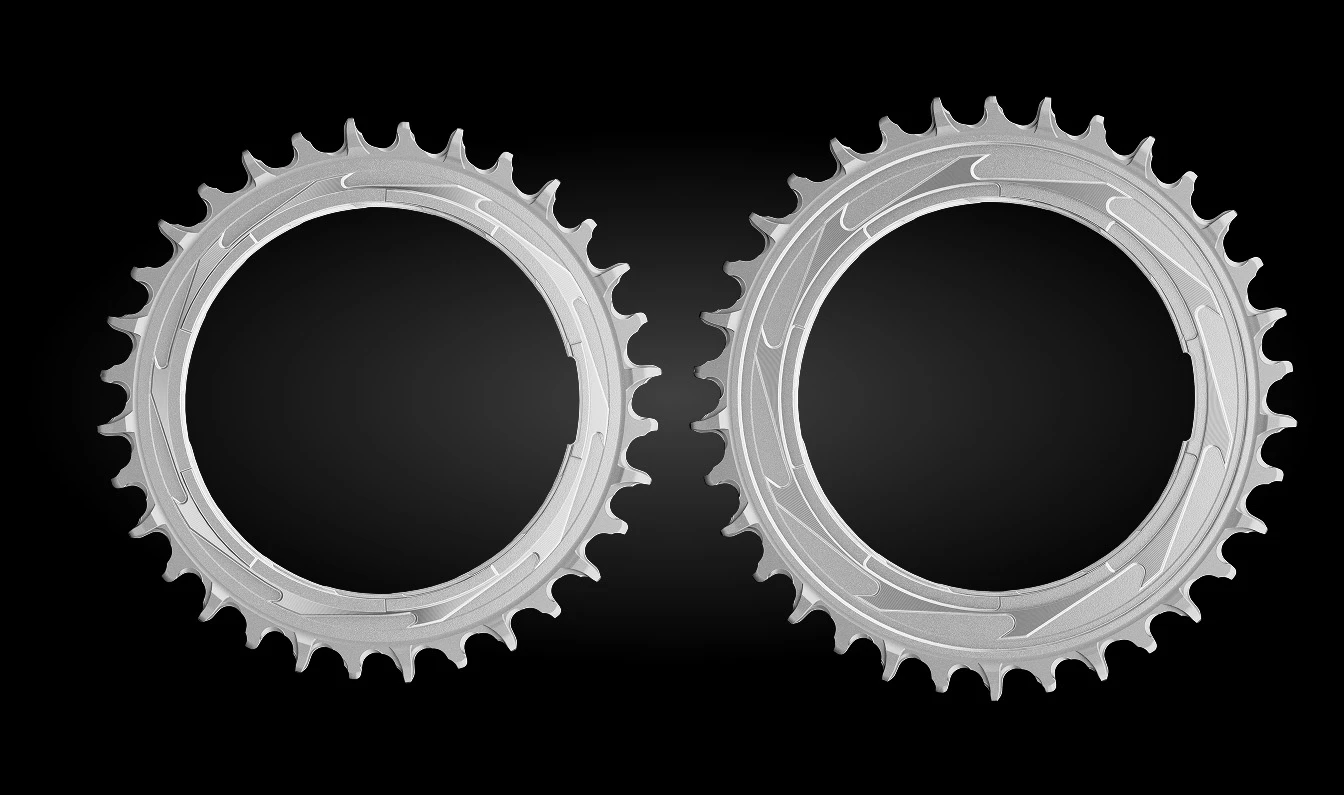 黒い背景に、2つの銀色の自転車用チェーンリングが並んでいる。.