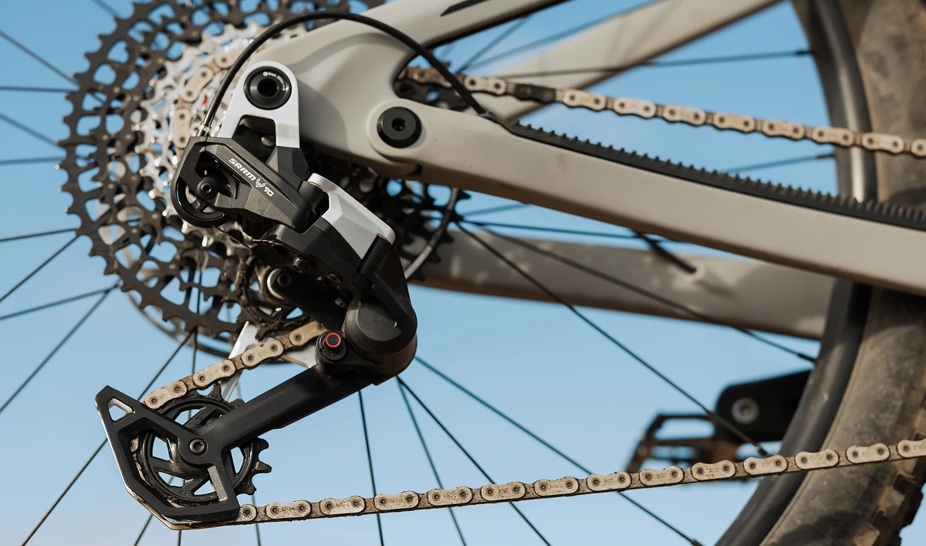 自転車のフレームに取り付けられた、SRAM製のマウンテンバイク用リアディレイラーとカセットのクローズアップ写真。.