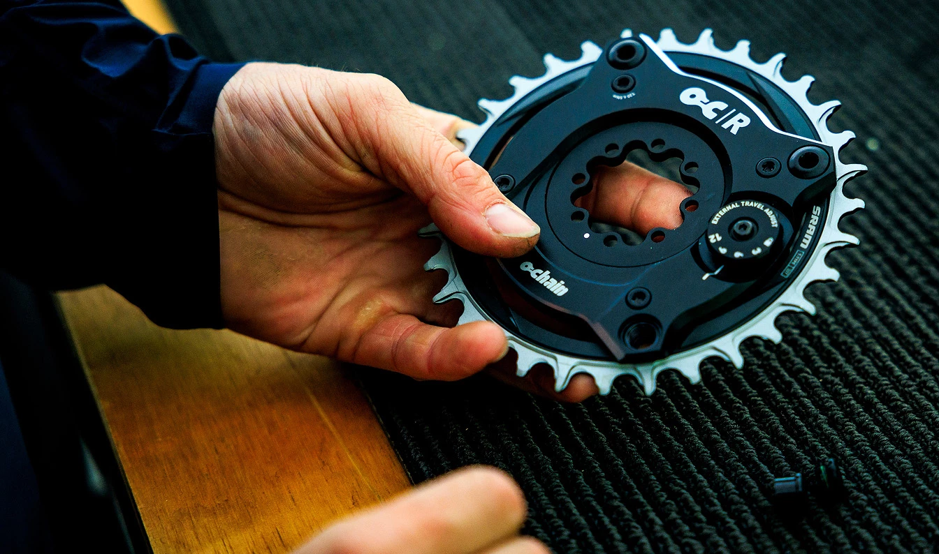 黒いO-Chainの自転車用チェーンリング部品を手に持っている手。.